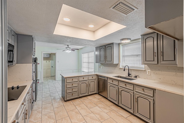 kitchen featuring a wainscoted wall, a peninsula, a sink, visible vents, and black appliances