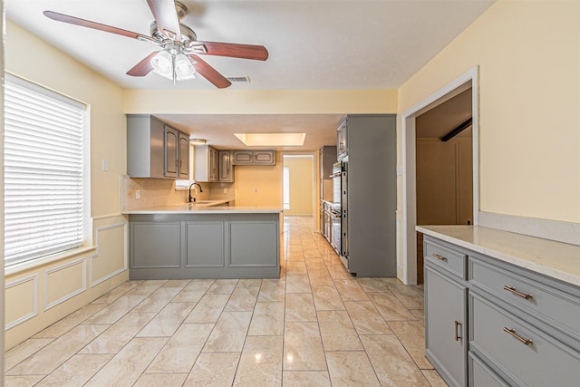 kitchen featuring a peninsula, visible vents, a ceiling fan, light countertops, and gray cabinets