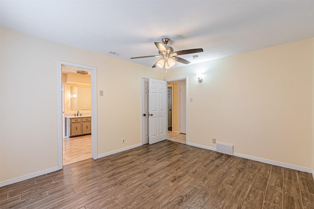 unfurnished bedroom featuring a sink, baseboards, visible vents, and wood finished floors