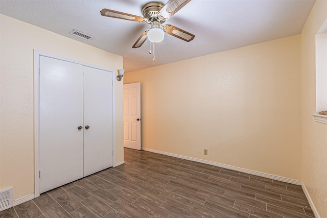 unfurnished bedroom with baseboards, visible vents, a ceiling fan, dark wood finished floors, and a closet