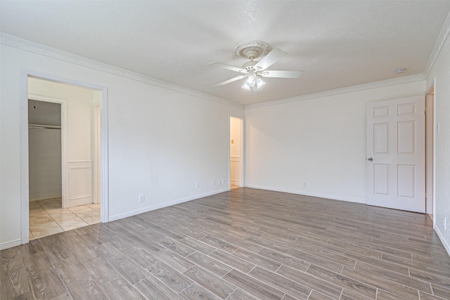 spare room with baseboards, wood finished floors, a ceiling fan, and crown molding