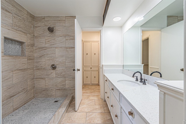 full bathroom with tiled shower and vanity