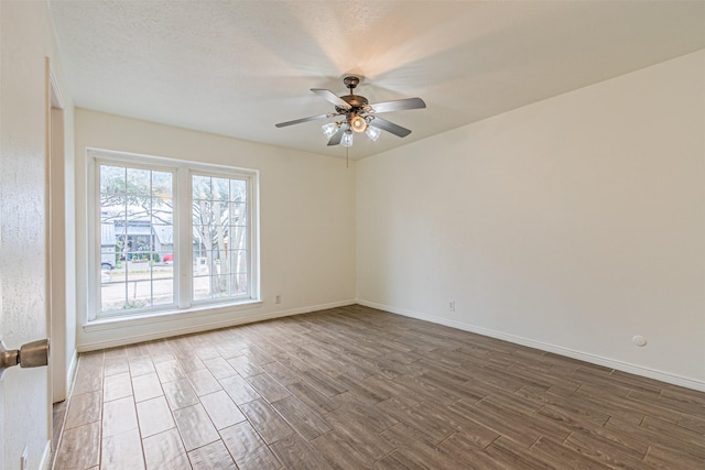 spare room featuring a ceiling fan, a textured ceiling, baseboards, and wood finished floors