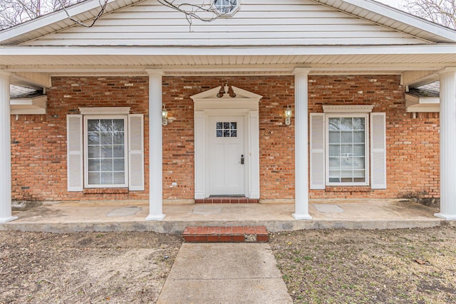 view of exterior entry with covered porch and brick siding