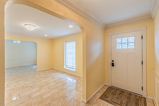 foyer entrance with arched walkways, ornamental molding, a wealth of natural light, and light wood-style floors