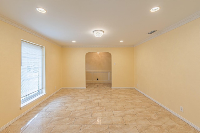 spare room featuring baseboards, visible vents, arched walkways, and crown molding