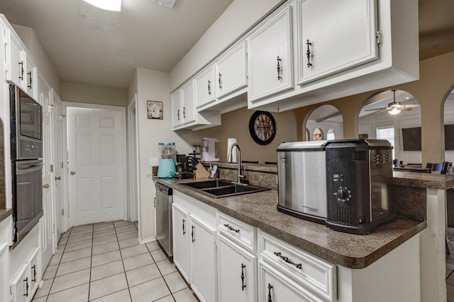 kitchen featuring wall oven, a sink, white cabinets, dishwasher, and dark countertops