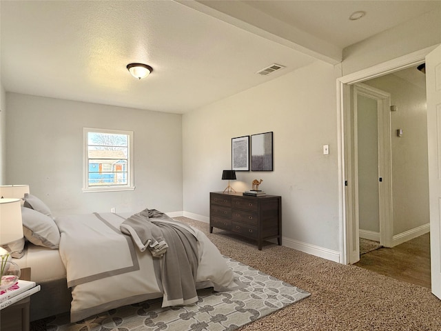 bedroom with baseboards, visible vents, and beam ceiling