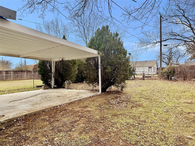 view of yard with driveway, fence, and a carport