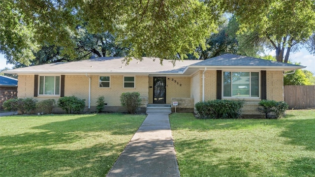 ranch-style home with brick siding, fence, and a front yard