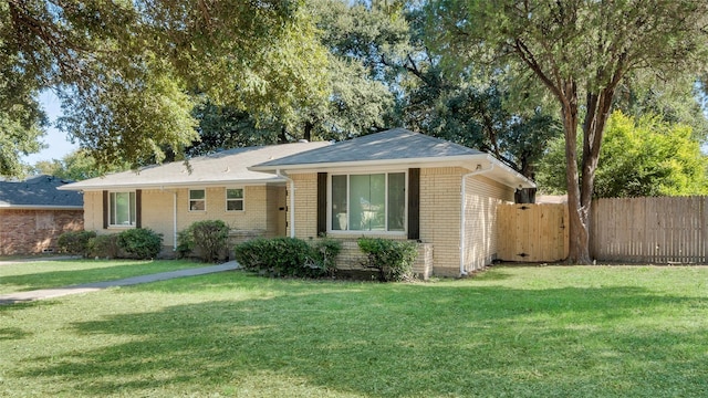 ranch-style home featuring a front yard, brick siding, and fence