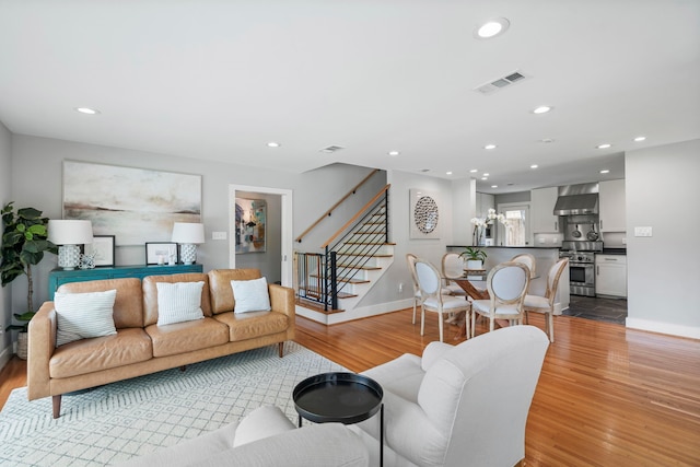 living area with light wood finished floors, stairway, and visible vents