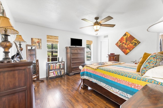 bedroom featuring a ceiling fan, visible vents, and dark wood finished floors