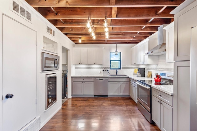 kitchen featuring decorative light fixtures, visible vents, appliances with stainless steel finishes, wall chimney range hood, and beverage cooler