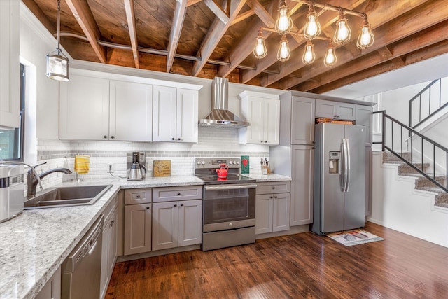 kitchen with stainless steel appliances, a sink, gray cabinets, wall chimney exhaust hood, and decorative light fixtures