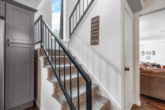 stairway featuring a textured ceiling, baseboards, and wood finished floors