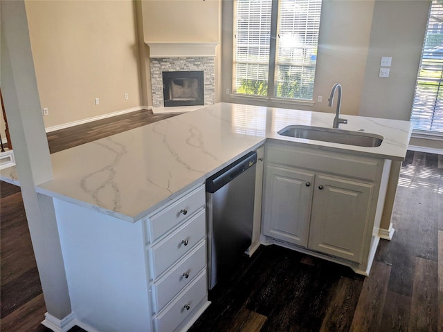 kitchen with white cabinets, light stone counters, open floor plan, a sink, and stainless steel dishwasher