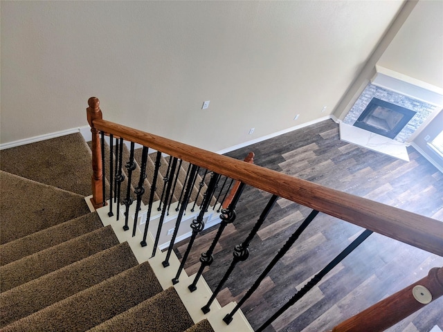 stairway featuring a fireplace, baseboards, and wood finished floors