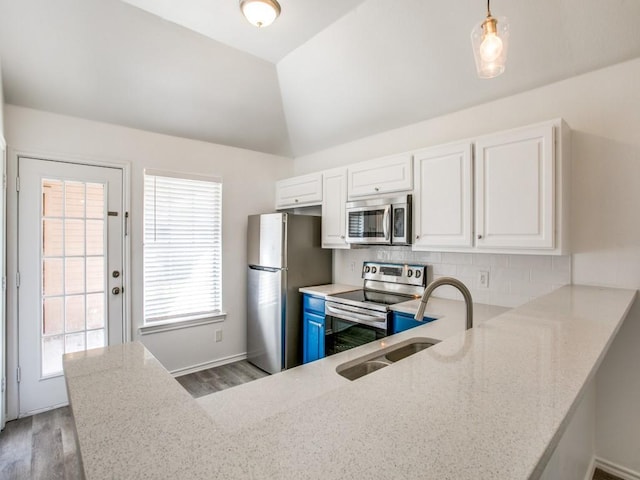 kitchen with a peninsula, appliances with stainless steel finishes, backsplash, and white cabinets