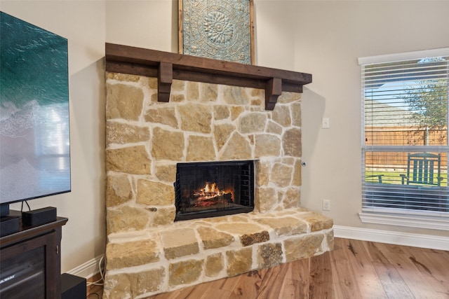 room details with a stone fireplace, baseboards, and wood finished floors