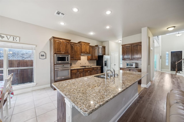 kitchen with appliances with stainless steel finishes, visible vents, a sink, and a large island