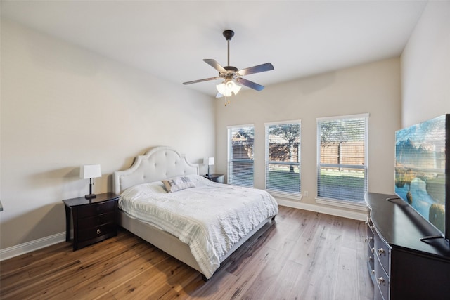 bedroom with ceiling fan, baseboards, and dark wood finished floors