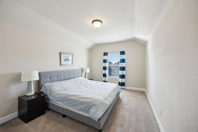 bedroom with lofted ceiling, light carpet, and baseboards