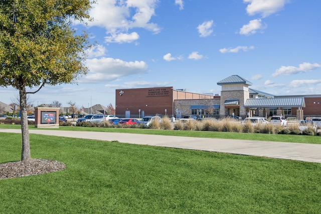 view of property's community featuring a lawn and concrete driveway