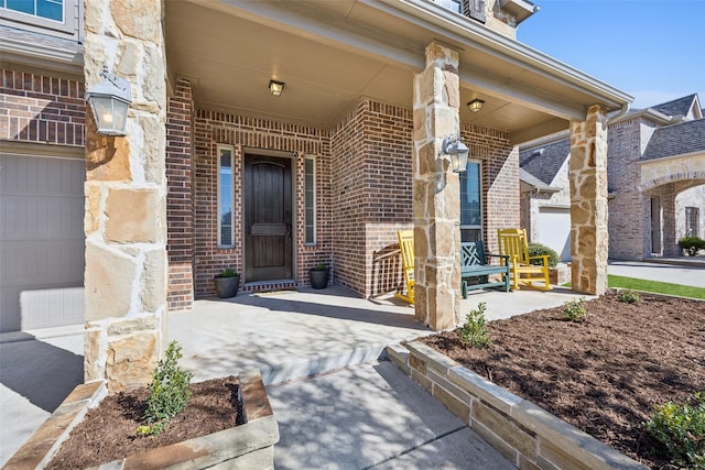 entrance to property featuring covered porch, brick siding, and a garage