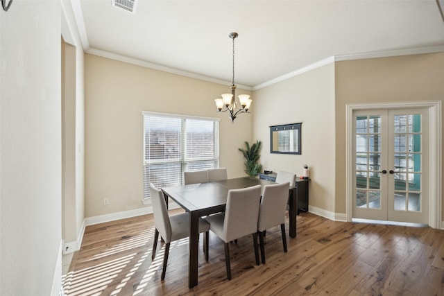 dining space featuring dark wood-style flooring, visible vents, baseboards, ornamental molding, and an inviting chandelier