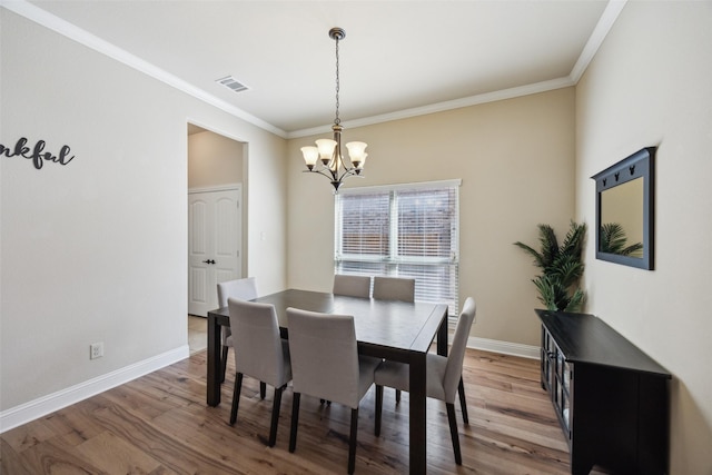 dining space featuring an inviting chandelier, baseboards, visible vents, and wood finished floors