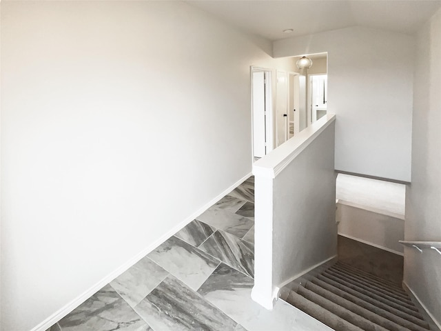 stairway with lofted ceiling, marble finish floor, and baseboards