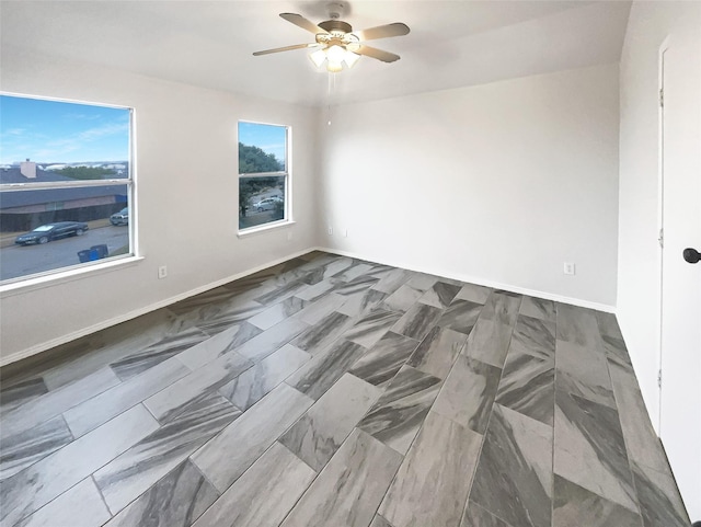 unfurnished room with ceiling fan and baseboards