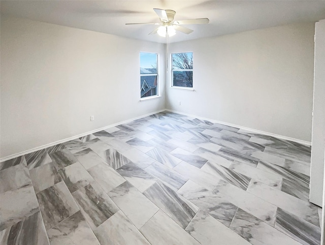 spare room featuring ceiling fan and baseboards