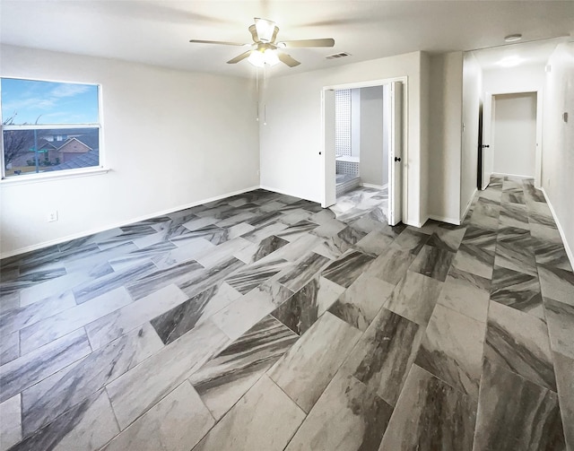 empty room featuring visible vents, ceiling fan, and baseboards