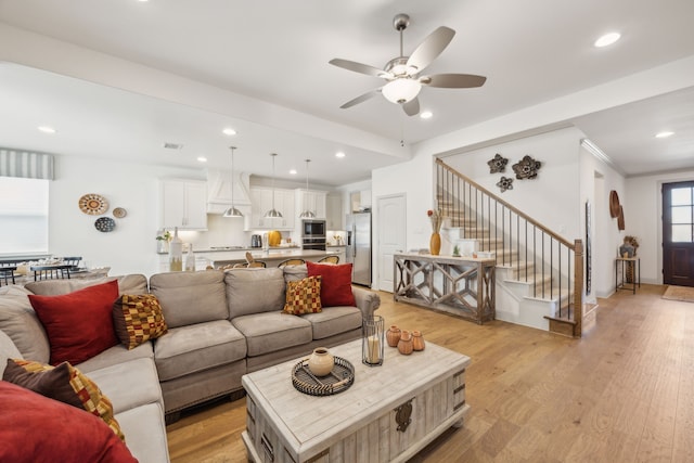 living area with light wood-type flooring, stairs, a ceiling fan, and recessed lighting