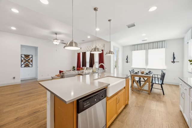 kitchen with light countertops, stainless steel dishwasher, open floor plan, a kitchen island with sink, and a sink