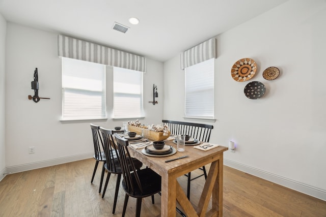 dining area featuring visible vents, light wood-style flooring, and baseboards