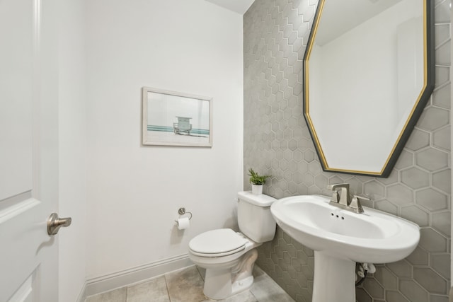 bathroom featuring toilet, baseboards, a sink, and tile patterned floors