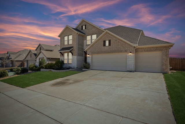 view of front of property with a garage, driveway, a shingled roof, a yard, and brick siding