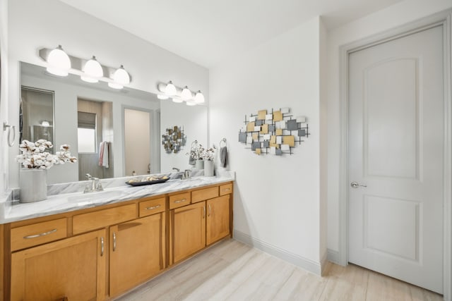 bathroom with double vanity, a sink, baseboards, and wood finished floors