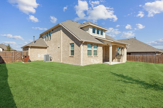 rear view of property featuring brick siding, a yard, and a fenced backyard