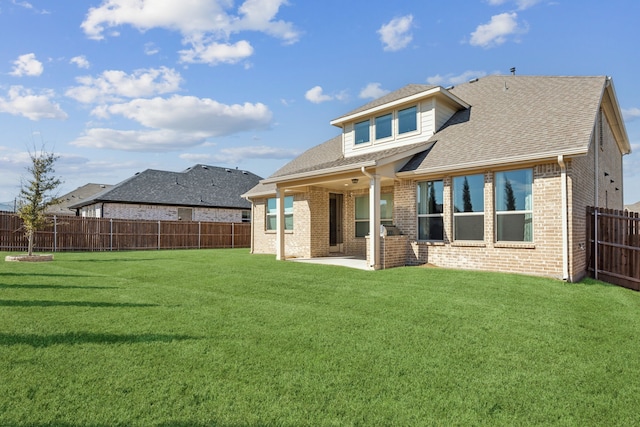 rear view of house with a lawn, a patio area, and a fenced backyard