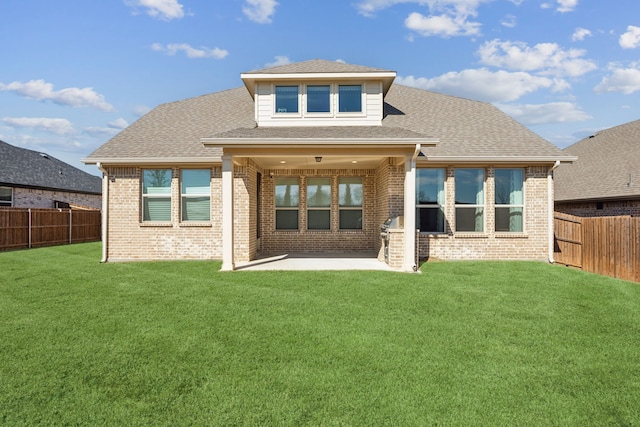 back of house with a yard, brick siding, a patio, and a fenced backyard