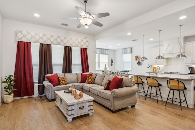 living area featuring light wood finished floors, visible vents, and a ceiling fan