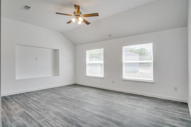 spare room with a wealth of natural light, visible vents, vaulted ceiling, and wood finished floors