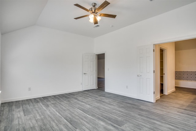 unfurnished bedroom featuring visible vents, vaulted ceiling, baseboards, and wood finished floors