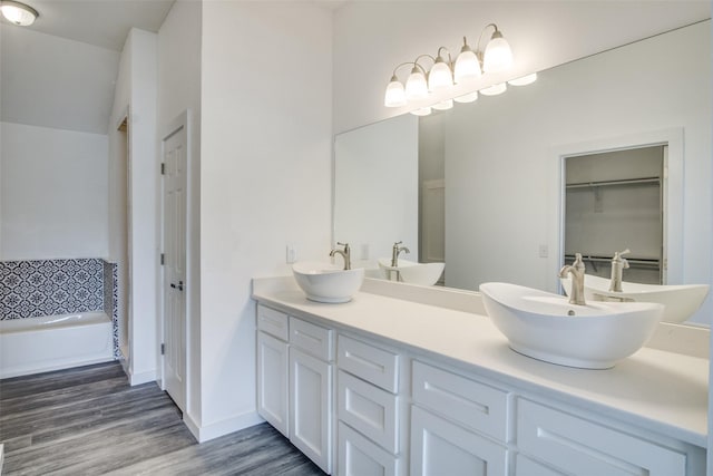 bathroom featuring double vanity, baseboards, a sink, and wood finished floors