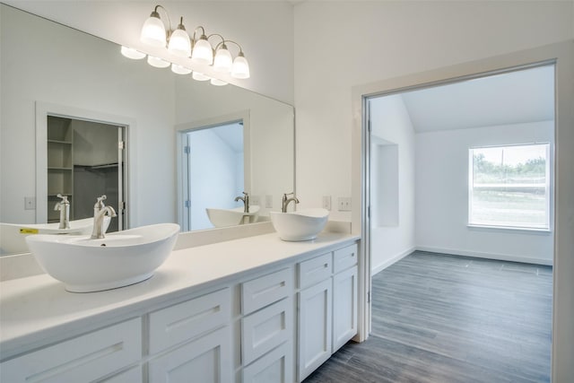 bathroom with double vanity, baseboards, a sink, and wood finished floors