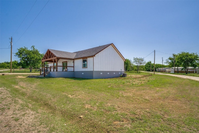 view of side of property featuring crawl space, roof with shingles, and a lawn